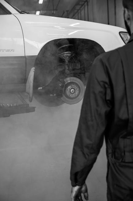 Mechanic approaches a lifted car in a workshop for inspection and maintenance.