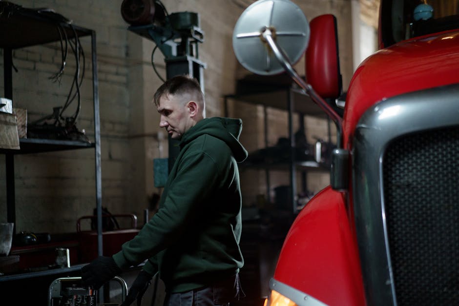 Mechanic in garage inspecting a red truck to ensure optimal performance.