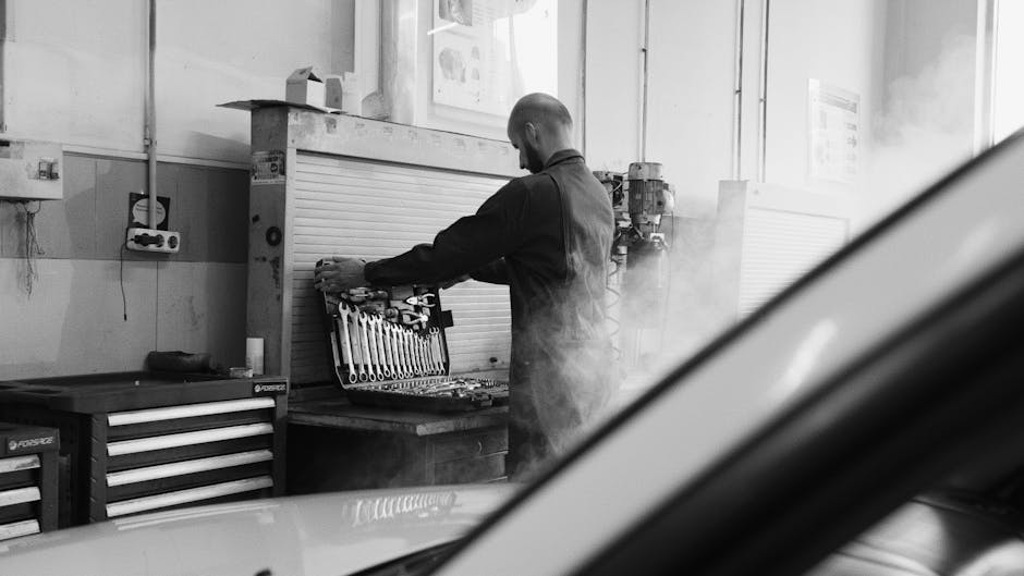 Mechanic working in a garage workshop with tools and equipment.