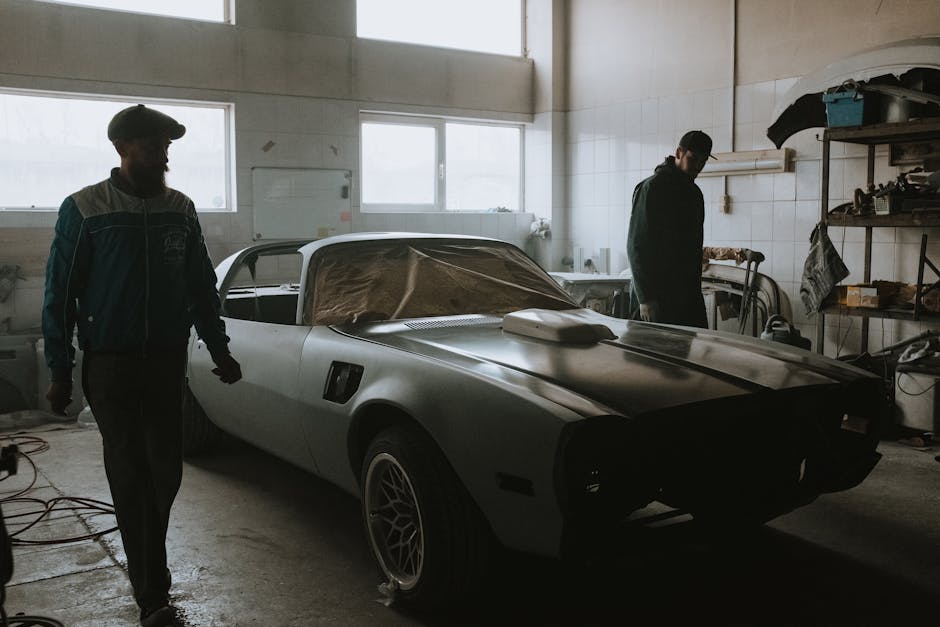 Mechanics working on a vintage car restoration in a dimly lit garage, capturing the essence of classic automotive care.